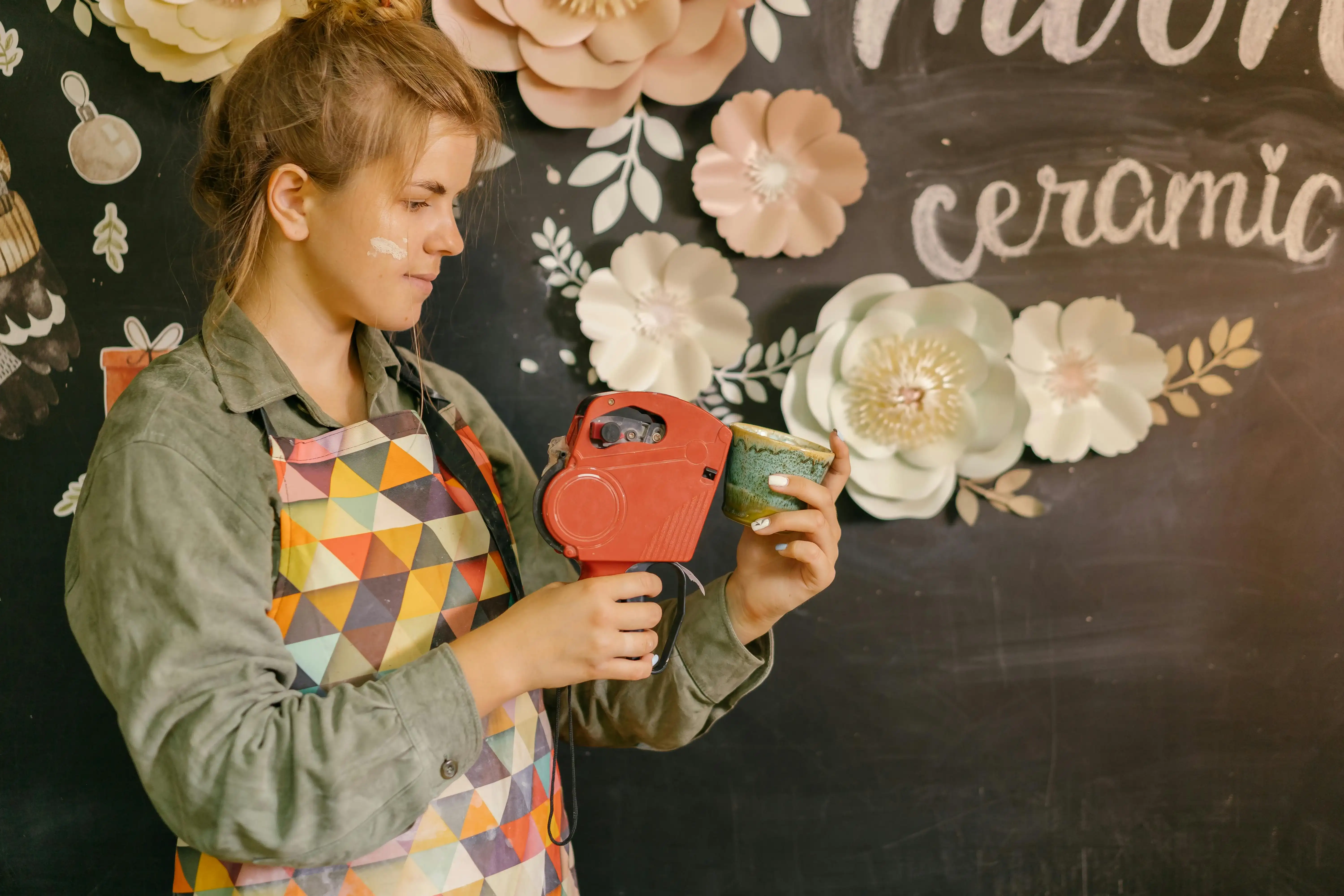 Maker labeling a handcrafted ceramic cup in a creative workspace